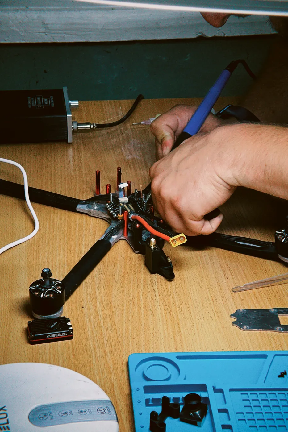 Hands assembling a drone on a workbench